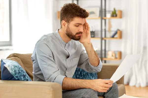 Unhappy man with bills or tax report at home — Stock Photo, Image
