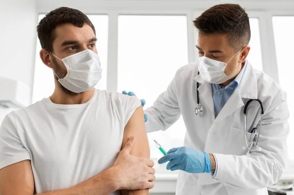 Patient et médecin masqués faisant la vaccination Photo De Stock