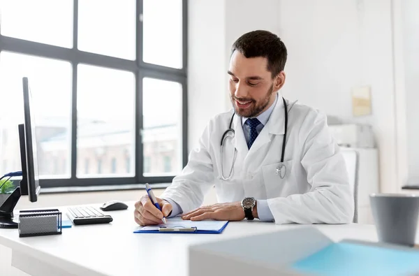 Sonriente médico masculino con portapapeles en el hospital —  Fotos de Stock