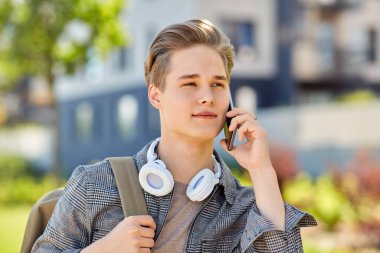 teenage student boy calling on smartphone in city clipart