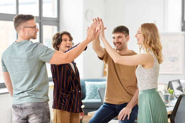 Glada affärsteam gör high five på kontoret — Stockfoto