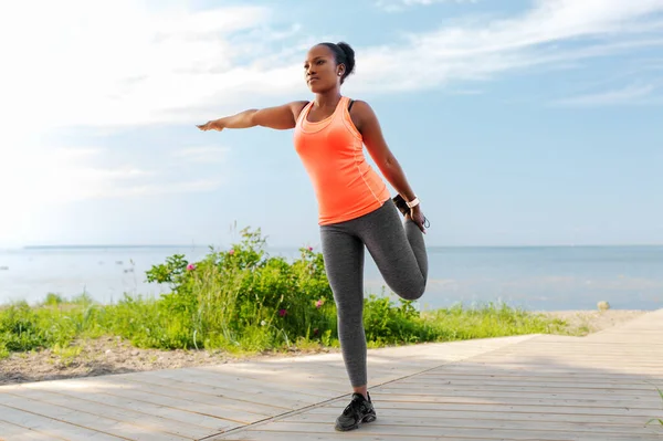 Jeune femme américaine africaine faisant de l'exercice sur la plage — Photo