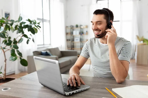 Hombre con auriculares y portátil trabajando en casa — Foto de Stock