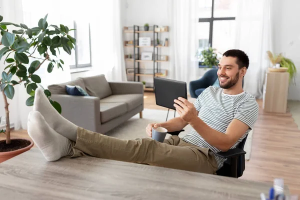 Homme avec tablette pc repose pieds sur la table à la maison — Photo