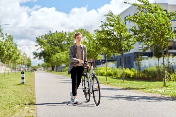 Giovane con bicicletta passeggiando lungo la strada della città — Foto Stock