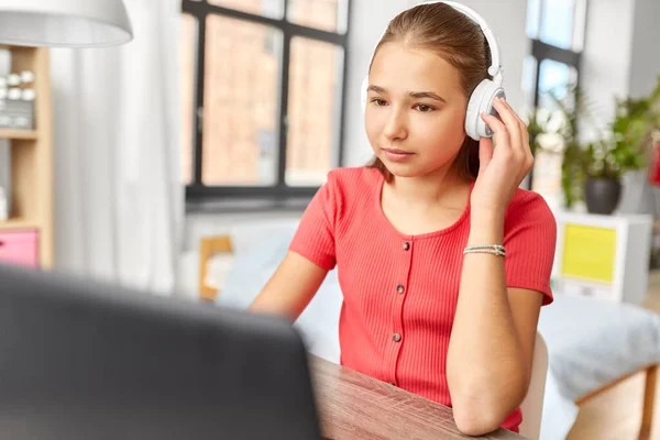 Menina em fones de ouvido com computador portátil em casa — Fotografia de Stock