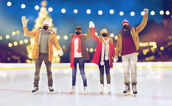 Friends in masks waving hands on skating rink — Stock Photo, Image
