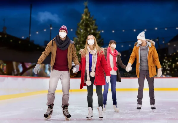 Vrienden in maskers op kerst schaatsbaan — Stockfoto