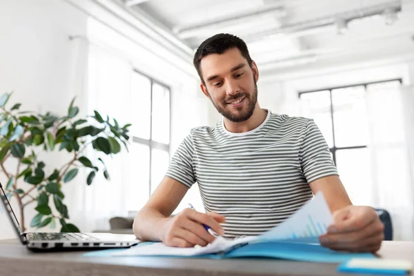 Uomo con documenti e laptop che lavora a casa ufficio — Foto Stock