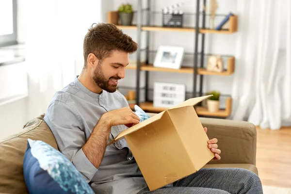 Glücklicher Mann öffnet Paketkasten zu Hause — Stockfoto