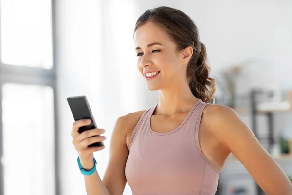 Mujer feliz con smatphone haciendo ejercicio en casa — Foto de Stock