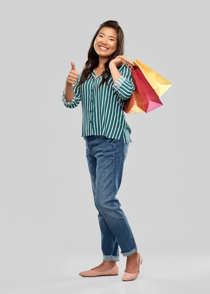 Asiático mujer con compras bolsas mostrando pulgares hasta —  Fotos de Stock