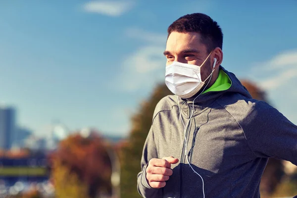 Hombre con máscara con auriculares corriendo en la ciudad —  Fotos de Stock