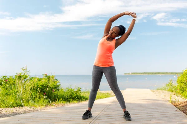 Joven afroamericana mujer haciendo ejercicio en la playa —  Fotos de Stock