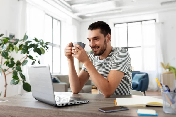 Bilgisayarlı bir adam ev ofisinde kahve içiyor. — Stok fotoğraf