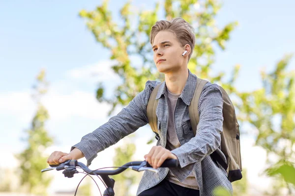 Student chłopiec z torbą i słuchawki jazda na rowerze — Zdjęcie stockowe