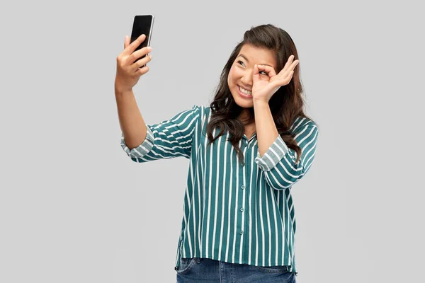 Smiling asian woman taking selfie by smartphone — Stock Photo, Image