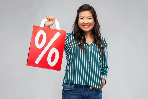 Asian woman with percentage sign on shopping bags — Stock Photo, Image