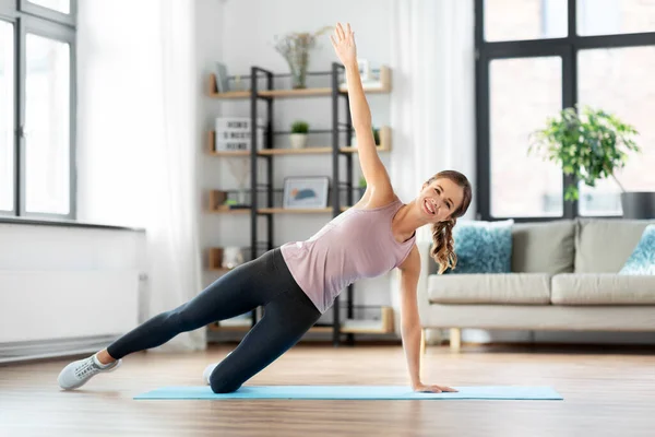 Mujer feliz haciendo ejercicio de tablón en la estera en casa — Foto de Stock