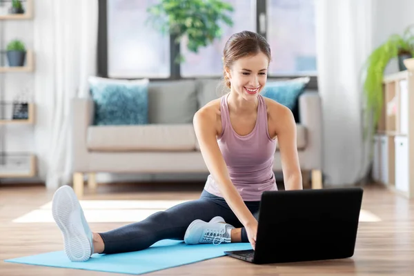 Mujer con computadora portátil haciendo deportes en casa — Foto de Stock