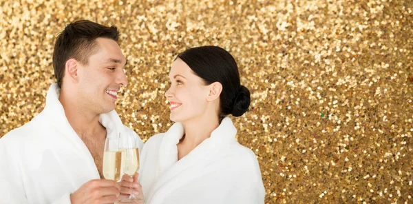 Happy couple in spa bath robes drinking champagne — Stock Photo, Image