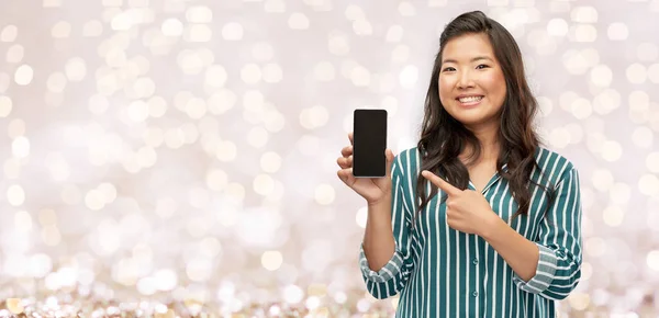 Happy asian woman with smartphone over lights — Stock Photo, Image