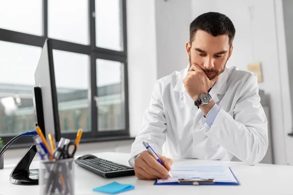 Stressed male doctor with clipboard at hospital — Stock Photo, Image