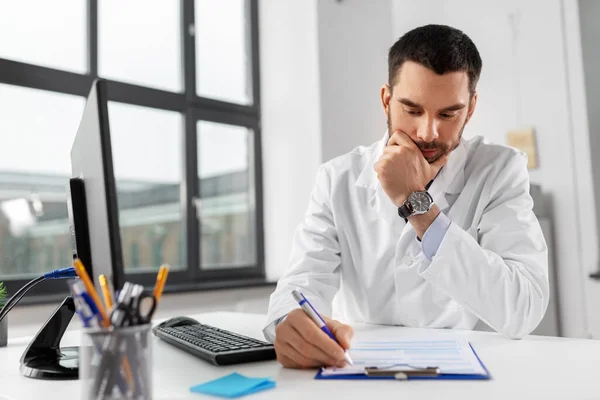 Docteur masculin stressé avec presse-papiers à l'hôpital — Photo