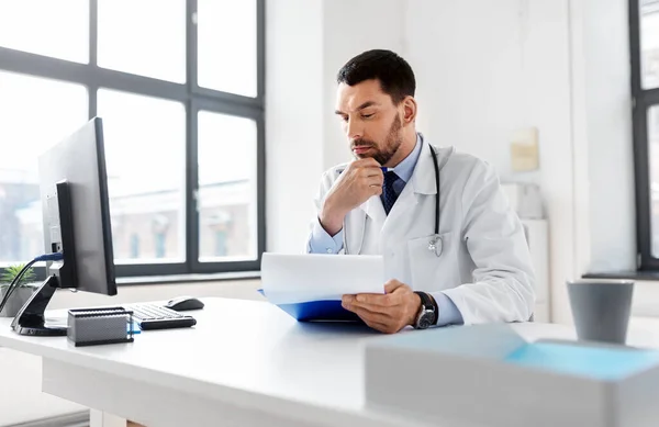 Gestresster Arzt mit Klemmbrett im Krankenhaus — Stockfoto