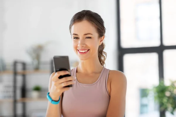 Mujer joven con smatphone haciendo ejercicio en casa —  Fotos de Stock