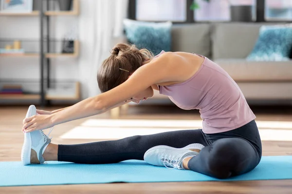 Mujer joven haciendo ejercicio de yoga en casa — Foto de Stock