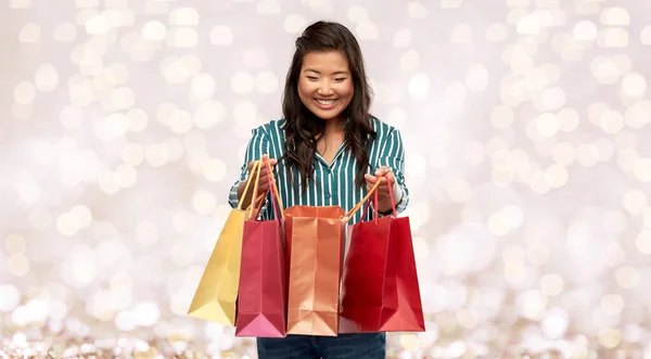 Feliz asiático mulher com compras sacos sobre luzes — Fotografia de Stock