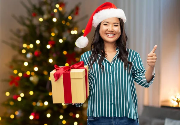 Asyalı kadın Noel hediyesiyle baş parmağını kaldırıyor. — Stok fotoğraf