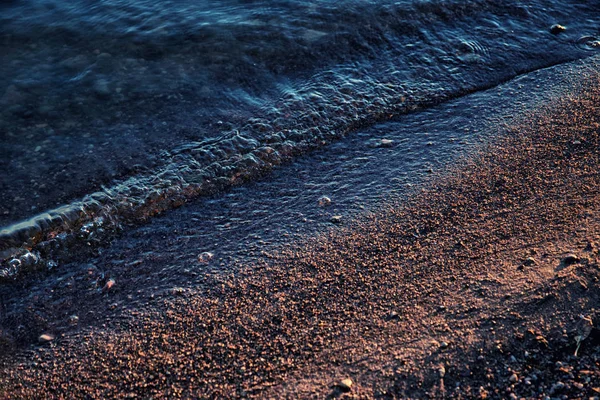 Kleine Wellen spülen einen Sandstrand entlang — Stockfoto