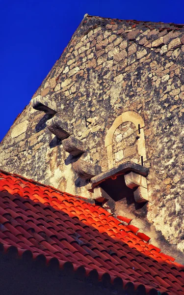 Eski çatı ve mavi gökyüzü karşı eski bir taş duvar karosu — Stok fotoğraf