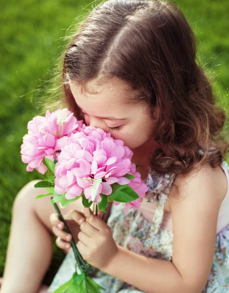 きれいでかわいい子を保持していると花をスニッフィング — ストック写真