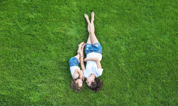 一个漂亮的母亲在清新的绿色草坪上和女儿一起放松的概念肖像 — 图库照片