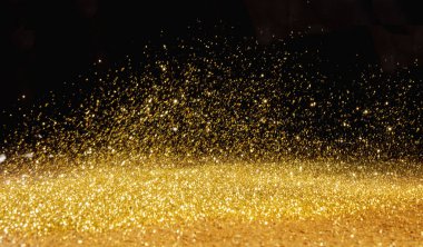Golden, shining powder scattered over the dark background clipart