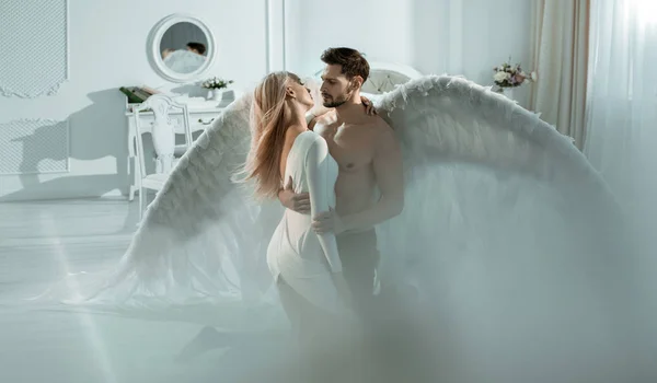 Retrato conceptual de un arcángel abrazando a una mujer hermosa — Foto de Stock