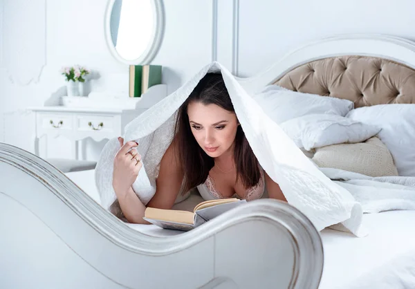 Relaxado senhora lendo um livro na cama Fotos De Bancos De Imagens Sem Royalties