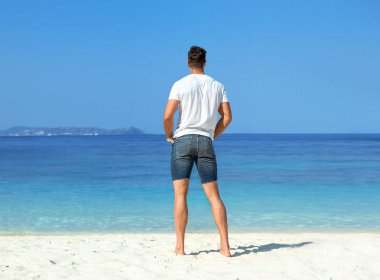 Yakışıklı, kaslı adam tropikal bir plajda rahatlatıcı