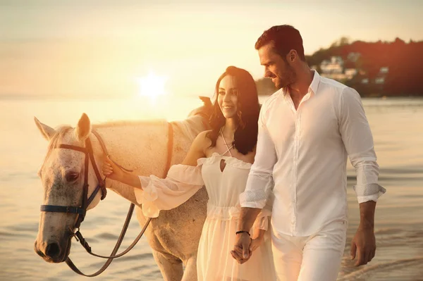 Jeune couple marchant sur un cheval majestueux - paysage balnéaire — Photo