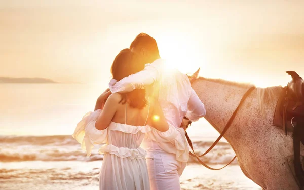 Giovane coppia a piedi un cavallo maestoso paesaggio balneare — Foto Stock