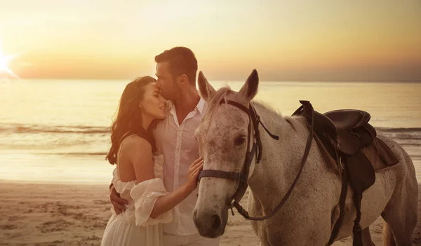 Giovane coppia a piedi un cavallo maestoso paesaggio balneare — Foto Stock