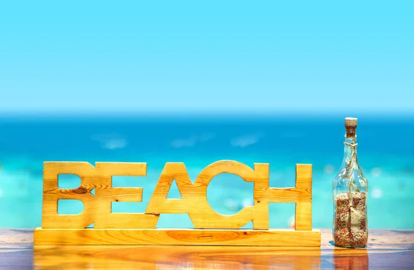 Trä inskription "strand" och lugnt hav i bakgrunden — Stockfoto