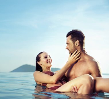 Genç, çekici bir çift sıcak, tropik bir havuzda dinleniyor.