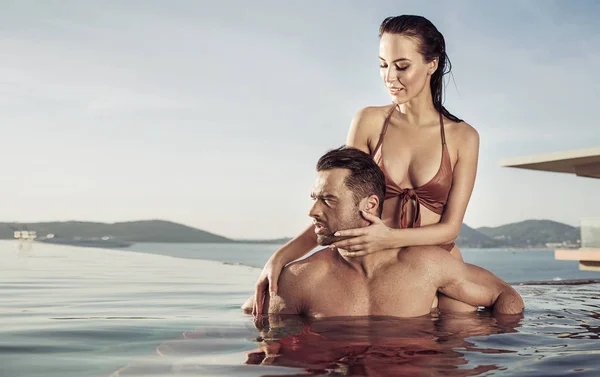 Casal jovem e atraente relaxando em uma piscina quente e tropical Imagens De Bancos De Imagens