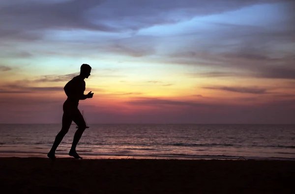 Jong, fit man doet joggen op een tropisch strand — Stockfoto