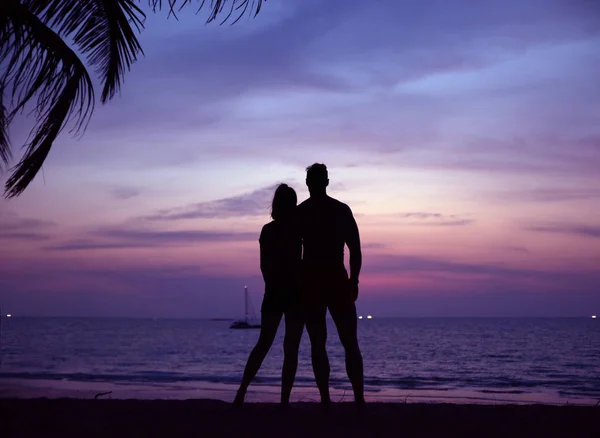 Casal relaxado assistindo a um pôr do sol tropical — Fotografia de Stock