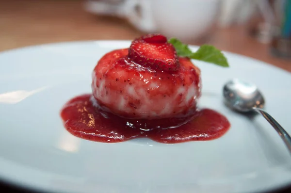 round ice cream with strawberry sauce with strawberries and mint